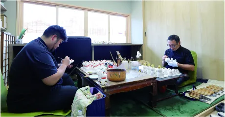 二寧坂にある店舗二階の工房で、息子の真親さんと向き合って人形を作る。